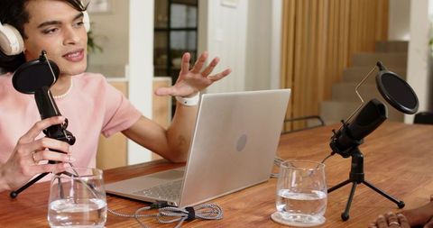 African american woman and male cohost recording podcast at cozy home studio with laptop