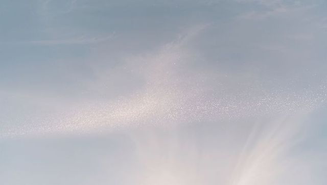 Pastel sky with glittering cloud band drifting across soft radiant horizon