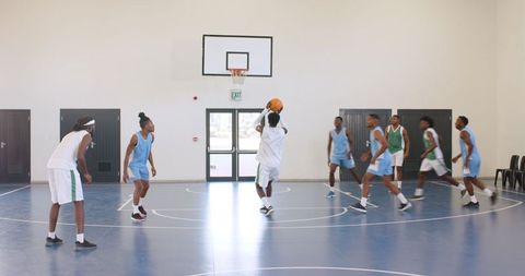 Basketball team on indoor court as player takes a jump shot