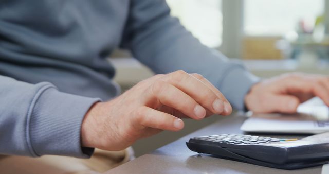 A middle-aged man is calculating expenses or budgeting, with copy space. His focus on the calculator suggests financial planning or accounting tasks at hand.