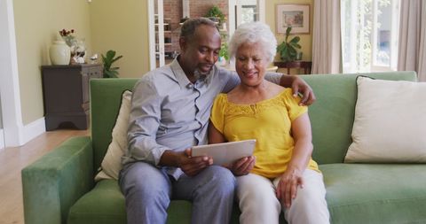 Happy Senior Couple Using Laptop on Sofa in Living Room