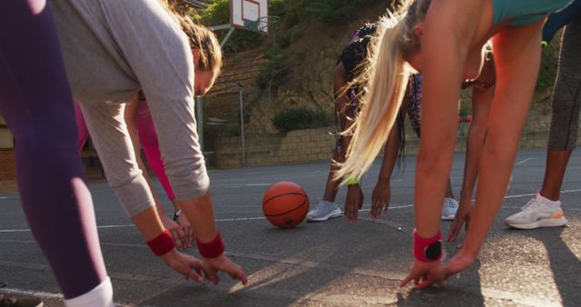 Female basketball players stretching together on an outdoor court, preparing for a game. Useful for promoting teamwork, fitness, and an active lifestyle. Ideal for sports, fitness, and health-related topics.