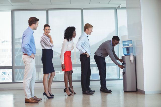 Business people standing in line by water cooler at office