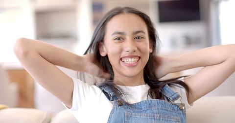 Smiling Teenage Girl in Denim Overalls Relaxing at Home