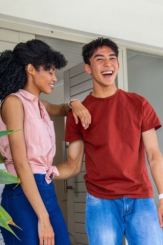 African american woman leaning on asian man laughing on porch lifestyle couple entering home