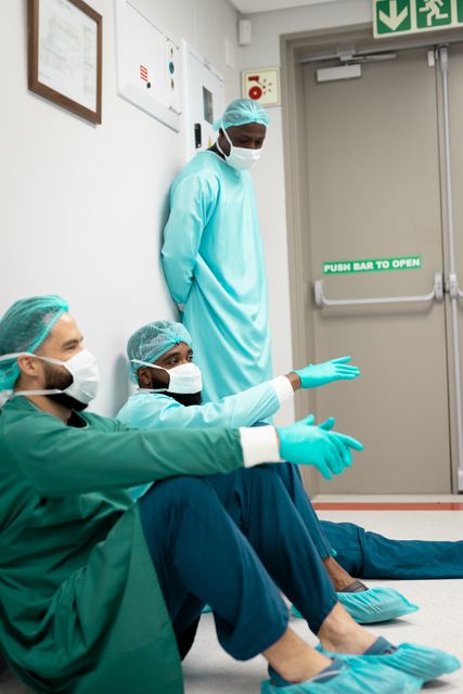 Three diverse male surgeons in scrubs and face masks, talking in hospital corridor - Download Free Stock Photos Pikwizard.com