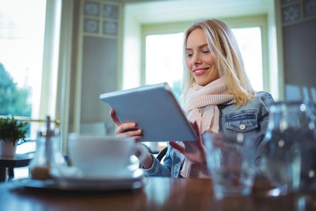 Smiling woman using digital tablet in cafe