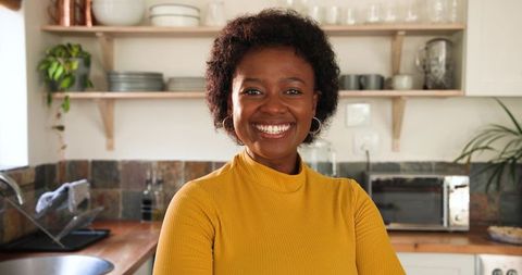 Smiling woman in cozy kitchen with wooden shelves
