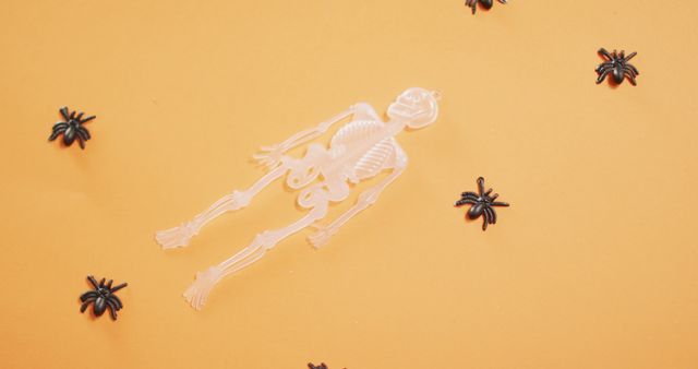 Multiple skeleton and spider toys with copy space against orange background. halloween festivity and celebration concept
