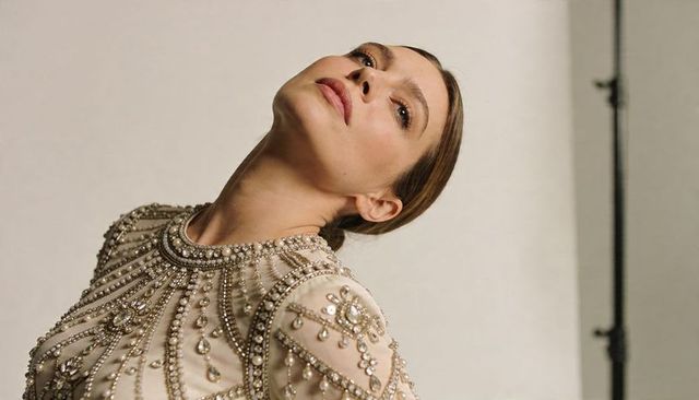 Model tilting head back in ornate beaded jeweled couture gown, luxe studio glamour portrait