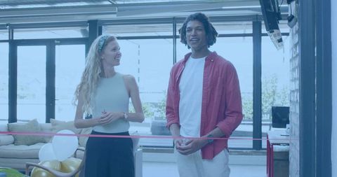 Young hosts conducting ribbon cutting ceremony in sunlit contemporary minimalist lounge