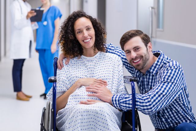 Portrait of man touching pregnant woman belly in corridor of hospital