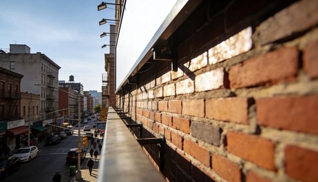 Sunlit Red-Brown Brick Facade Running Along Metal Rail Overlooking Urban Street at Golden Hour