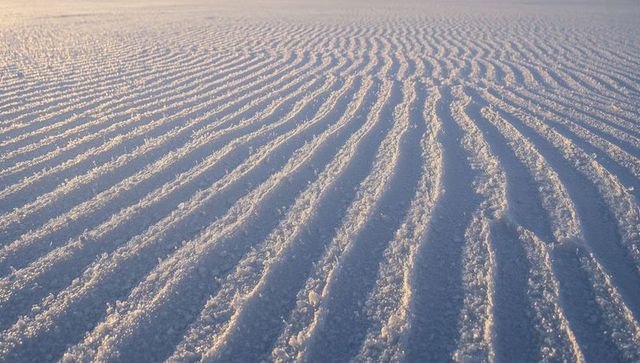 Glinting rippled salt flats at sunrise with parallel crystalline ridges and patterns