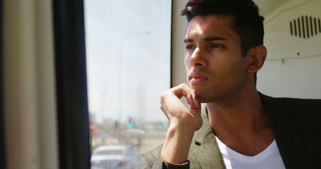 Young man thinking while gazing out train window - Download Free Stock Images Pikwizard.com