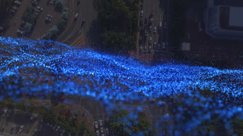 Digital Animation of Blue Particles Over Cityscape
