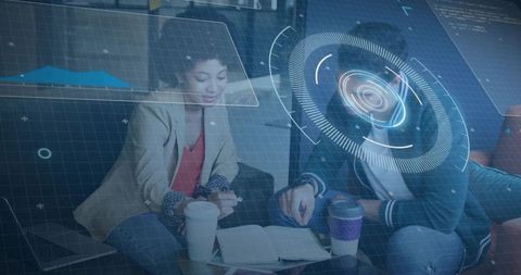 Two colleagues collaborating over notebook with augmented reality hud in coworking lounge