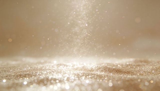 Shimmering golden glitter sparkling on warm metallic surface with bokeh and glowing dust