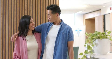 Smiling young couple sharing affectionate moment in modern lobby with wood slat wall