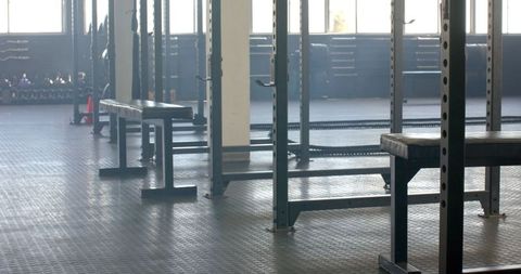 Empty Gym with Weightlifting Equipment and Benches Under Sunlight