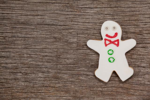 Gingerbread man decorated with icing in festive colors on rustic wooden surface. Ideal for Christmas cards, holiday-themed advertisements, festive social media posts, baking blogs, seasonal menus, and craft projects.