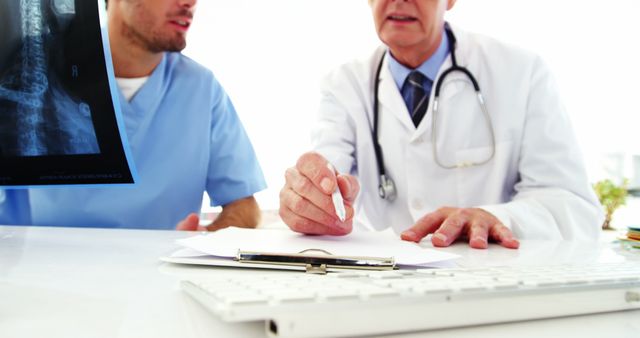 A Caucasian doctor is discussing medical records with a healthcare colleague, with copy space. They are focused on providing quality patient care through collaboration and expertise.