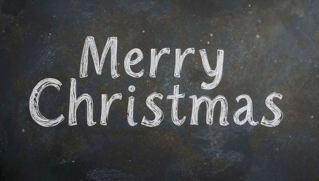 Merry christmas chalk lettering on rustic blackboard showing chalk dust and texture