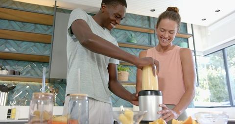 Diverse Young Couple Enjoy Preparing Healthy Smoothie in Kitchen