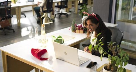 Indian professional celebrating office holiday during virtual meeting in festive open-plan workspace