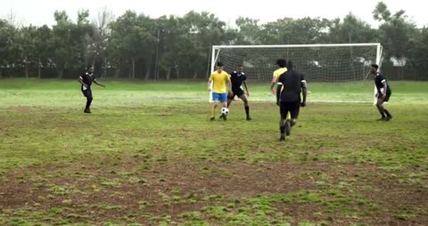 Soccer Players Competing on Muddy Field for Goal