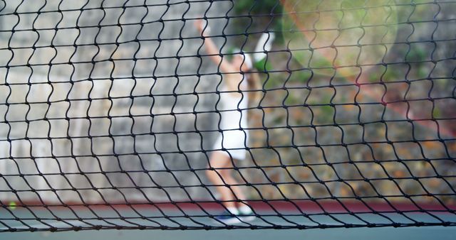 Blurred Tennis Player Serving Behind Net on Outdoor Court - Download Free Stock Images Pikwizard.com