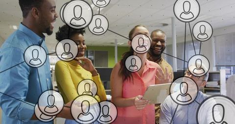 Collaborating diverse team sharing ideas around tablet in open-plan office network overlay