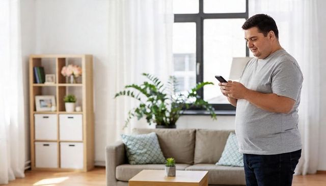 Man checking smartphone in bright modern living room, relaxed home tech lifestyle