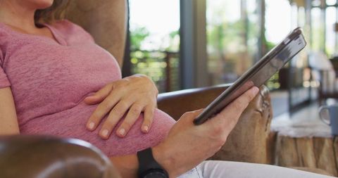 Pregnant Woman Relaxing in Armchair with Tablet