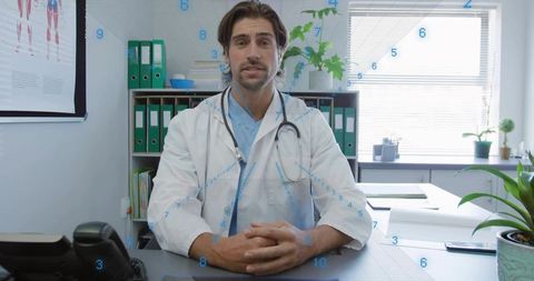 Male doctor consulting patient and reviewing records at clinic desk using smartphone and stethoscope