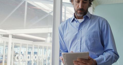 Focused Businessman Reviewing Data on Tablet in Office