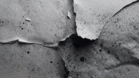 Peeling paint layers revealing dark underlayer in slow pan close-up