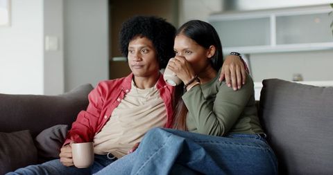 Cozy Couple Enjoying Coffee at Home on Grey Sofa