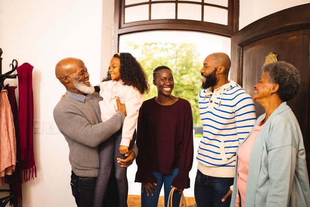 Happy african american senior man and woman welcoming family at entrance in house. Unaltered, copy space, multi-generation family, love, together, childhood, gathering, lifestyle and winter concept.