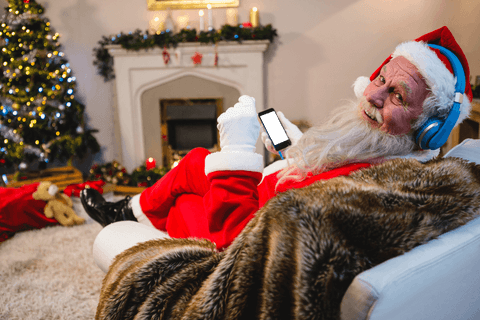 Santa Claus in Red Suit Relaxing with Smartphone and Headphones