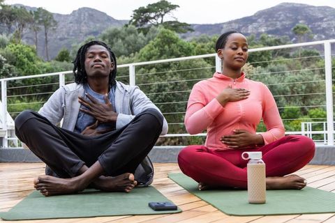 African american friends practicing mindful breathing and meditating on outdoor deck