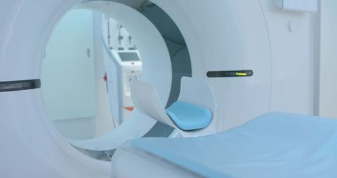Ct scanner gantry with patient bed and blue headrest in clean diagnostic radiology room