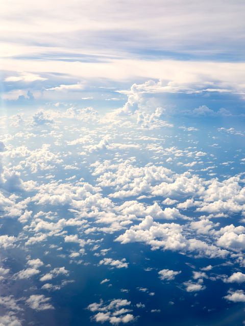 Capturing an aerial perspective of fluffy clouds scattered across the remote blue sky. Perfect for use in weather forecasts, travel promotions, and nature documentaries. Ideal background for inspirational quotes and relaxing visuals in presentations.