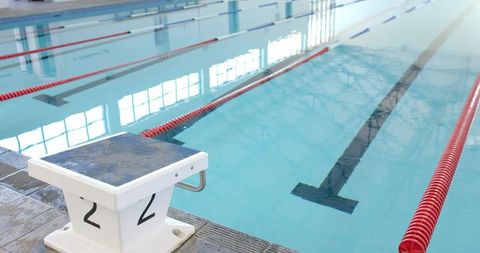 Competition starting block number 2 at indoor swimming pool with red lane dividers