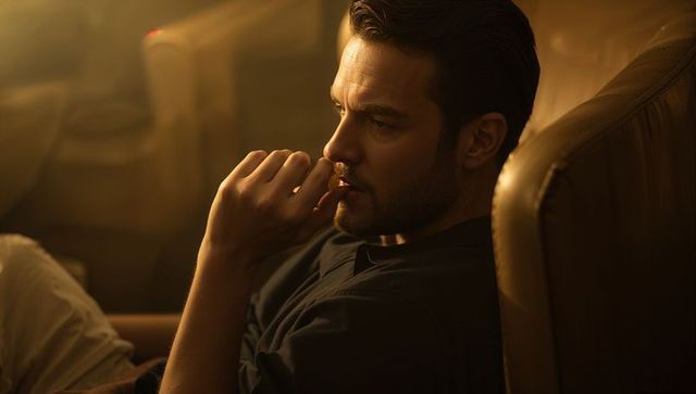 Pensive man reclining in leather armchair bathed in warm cinematic amber light