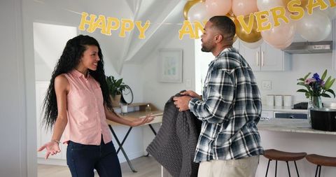 Joyful couple cleaning after home anniversary celebration