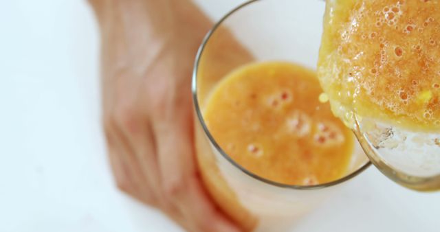 Bright and refreshing image of fresh orange juice being poured into a glass from a close-up perspective. Ideal for use in healthy living blogs, beverage advertisements, and nutrition articles emphasizing the benefits of vitamin C and fresh juices.