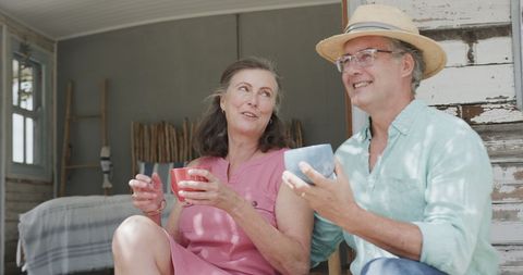 Cheerful Senior Couple Enjoying Coffee on Beach Porch