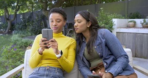Two Diverse Friends Sharing Smartphone Moments Outdoors