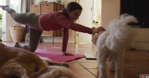 Woman Practicing Yoga at Home with Dogs and Laptop Nearby